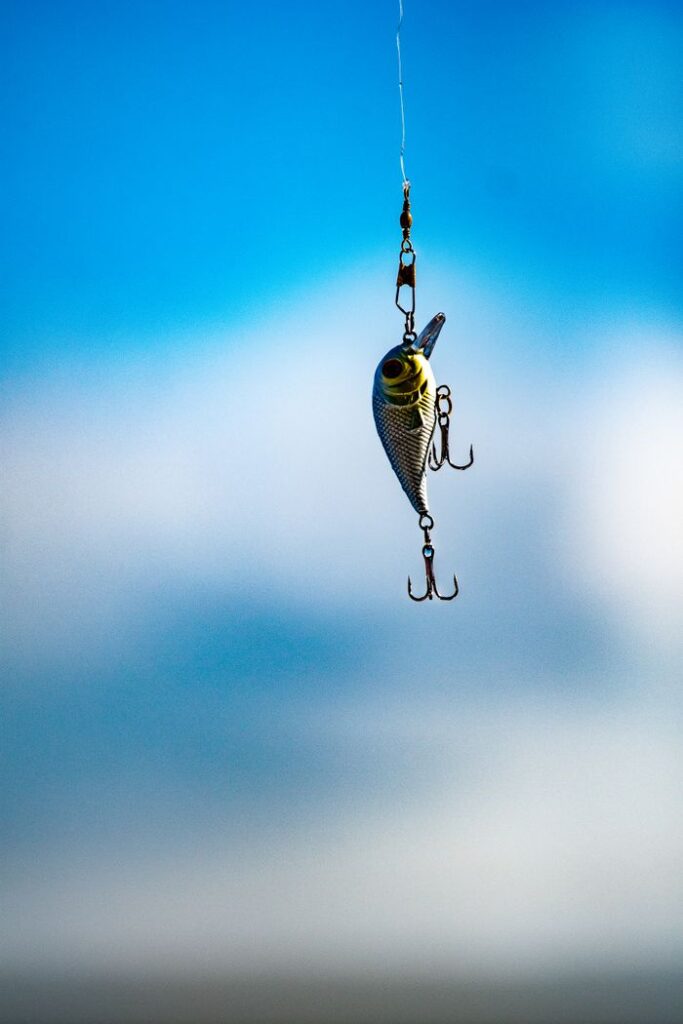 The Art of Drawing Readers In: Your attractive post title goes here Metallic fishing lure with hooks suspended in mid-air against a bright blue sky.